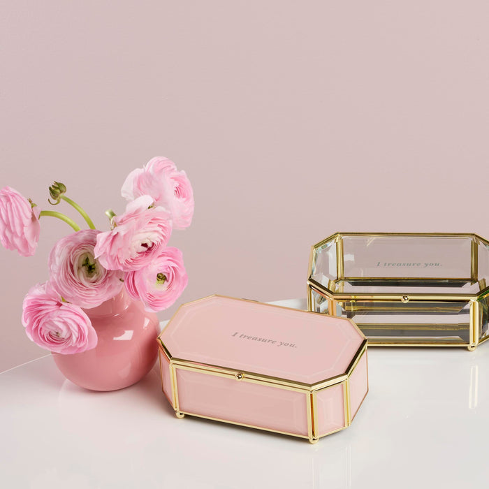Pink hexagonal jewelry box and pink vase with flowers on a light background